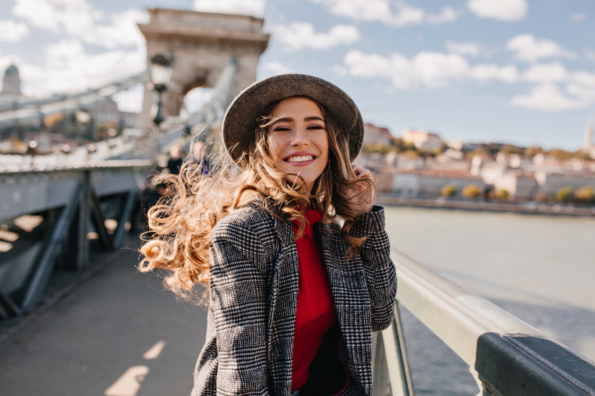Ein lächelndes Mädchen mit Hut und auf einer Brücke stehend