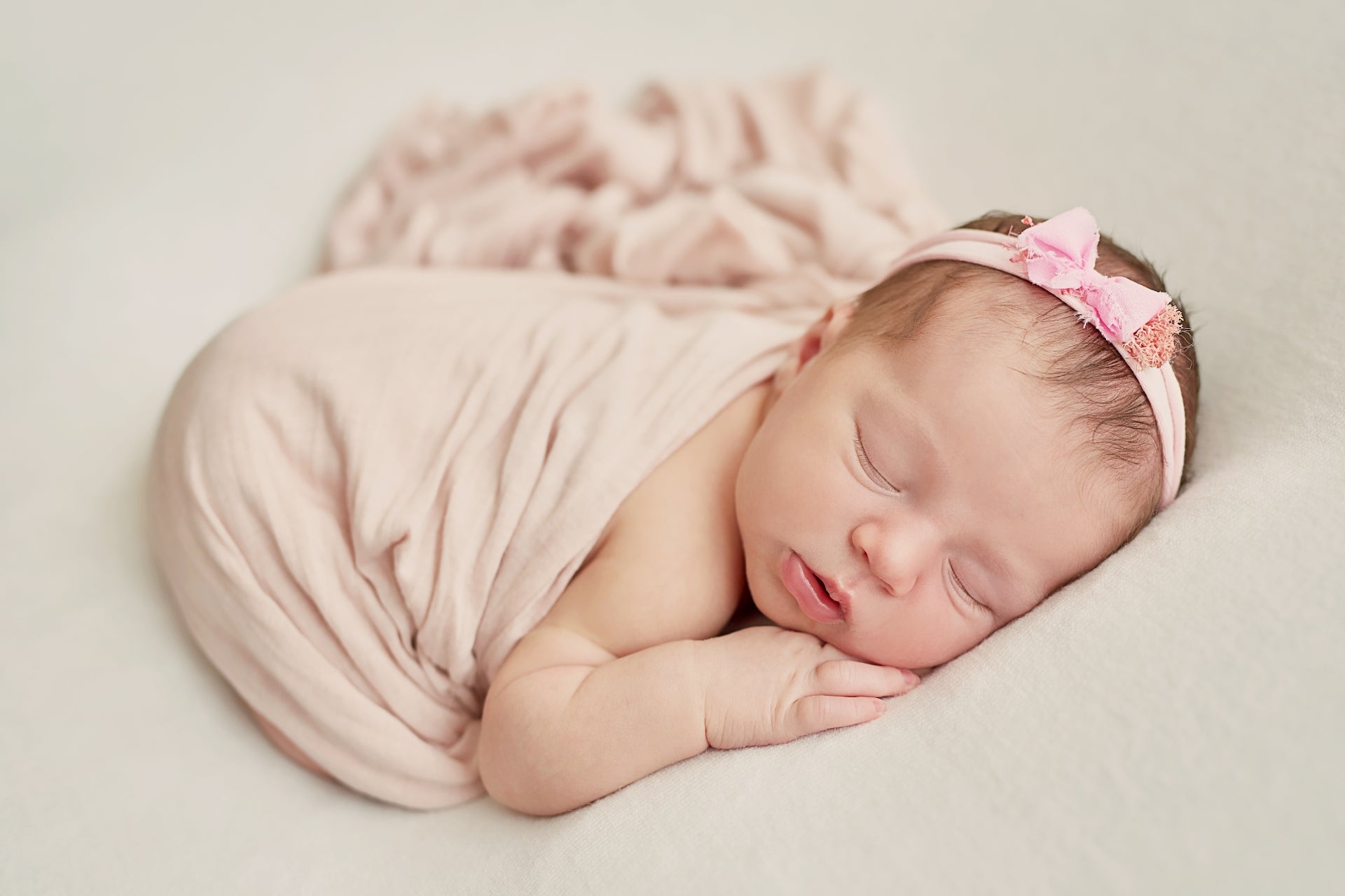 Neugeborenes Mädchen schläft in rosa Stoff gehüllt