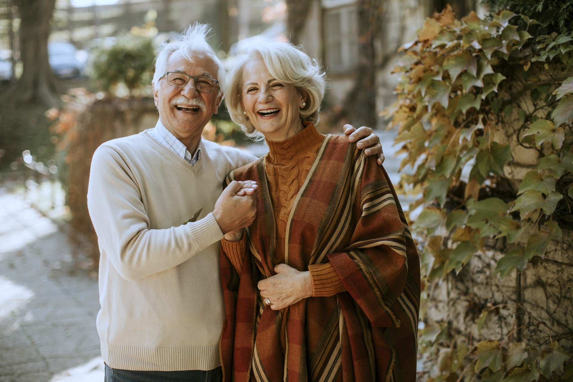 Älteres Ehepaar umarmt und lacht im Herbstpark